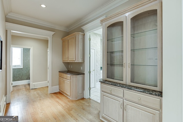 interior space with dark stone counters, light brown cabinets, light hardwood / wood-style floors, and crown molding