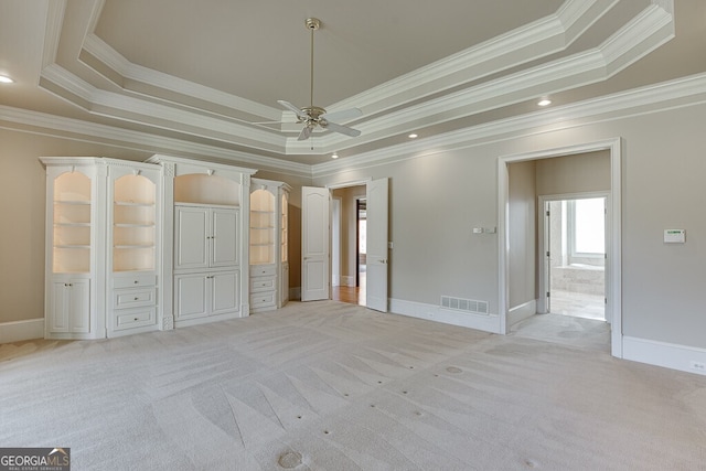 unfurnished bedroom with ceiling fan, ornamental molding, a tray ceiling, and light carpet