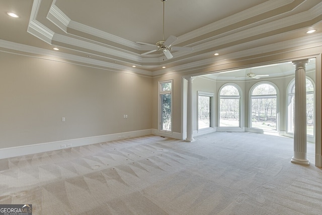 carpeted empty room featuring ceiling fan, crown molding, decorative columns, and a raised ceiling