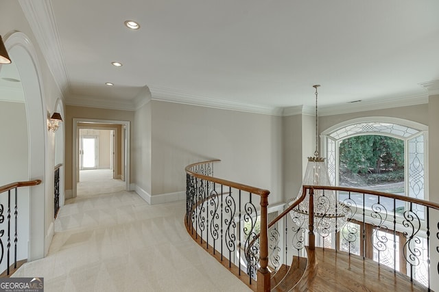 corridor featuring light carpet, a chandelier, and crown molding