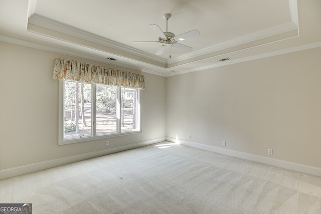 spare room with ceiling fan, a raised ceiling, and light colored carpet