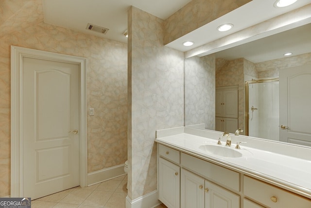 bathroom featuring tile floors, toilet, vanity, and a shower with shower door