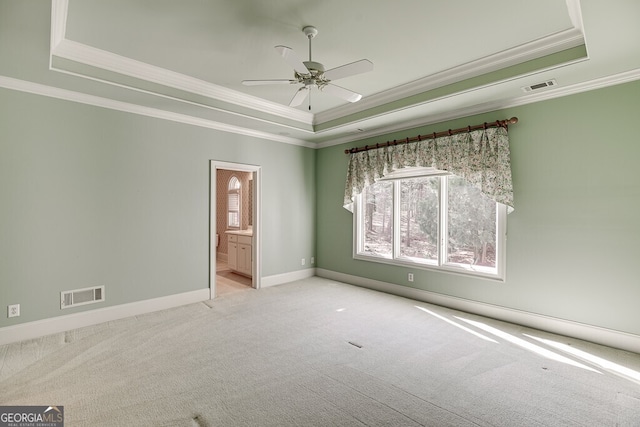 unfurnished room featuring light colored carpet, a tray ceiling, and ceiling fan