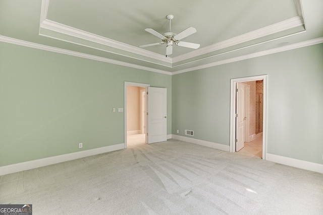 unfurnished room with ceiling fan, crown molding, light colored carpet, and a tray ceiling