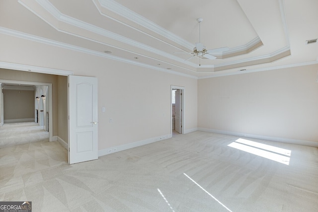 carpeted empty room featuring ceiling fan, ornamental molding, and a raised ceiling