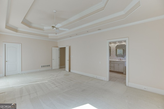 spare room featuring sink, ceiling fan, a raised ceiling, crown molding, and light carpet