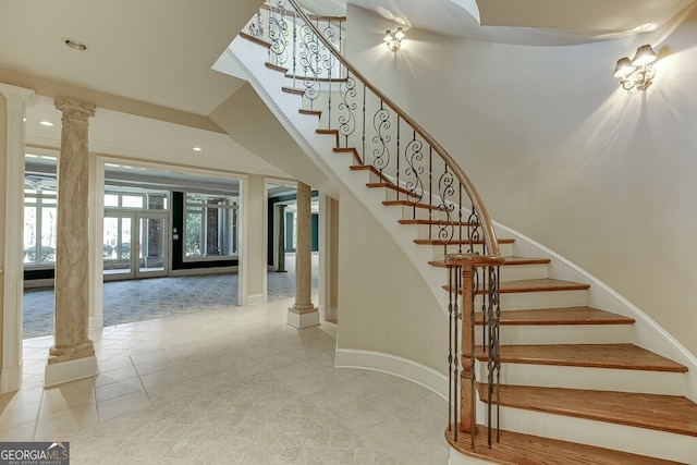 stairs with ornate columns and light tile flooring