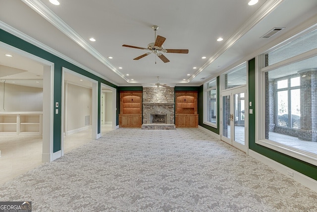 unfurnished living room with ceiling fan, built in shelves, ornamental molding, and a fireplace