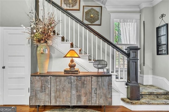 stairs with wood-type flooring and crown molding