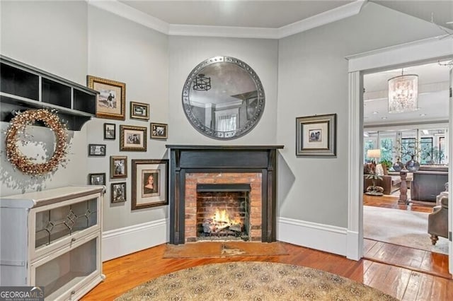 living area with crown molding, light hardwood / wood-style flooring, and a brick fireplace