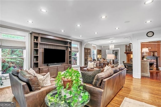 living room featuring a wealth of natural light, crown molding, and light wood-type flooring