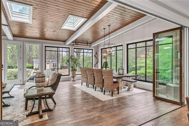 sunroom with a chandelier, wooden ceiling, and vaulted ceiling with skylight