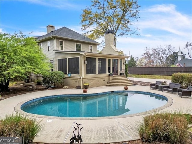 rear view of house with a patio, a sunroom, and a fenced in pool