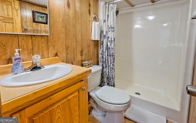 bathroom featuring walk in shower, toilet, vanity, and wood walls