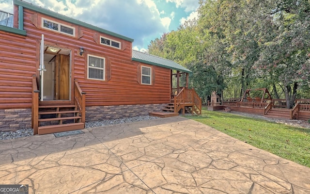 back of property with a wooden deck and a patio area