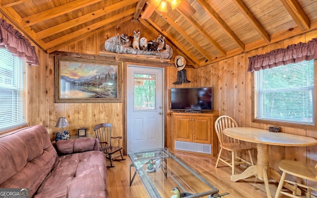 living room with light hardwood / wood-style floors, ceiling fan, wood ceiling, wooden walls, and lofted ceiling with beams