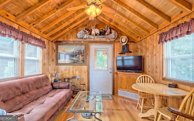 living room with vaulted ceiling with beams, ceiling fan, wood ceiling, wooden walls, and light hardwood / wood-style flooring