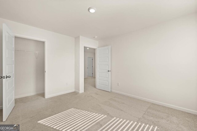 unfurnished bedroom with light carpet and a closet