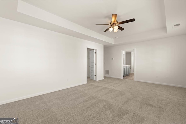 unfurnished room featuring light carpet, ceiling fan, and a tray ceiling