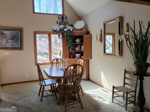 carpeted dining space with high vaulted ceiling and an inviting chandelier