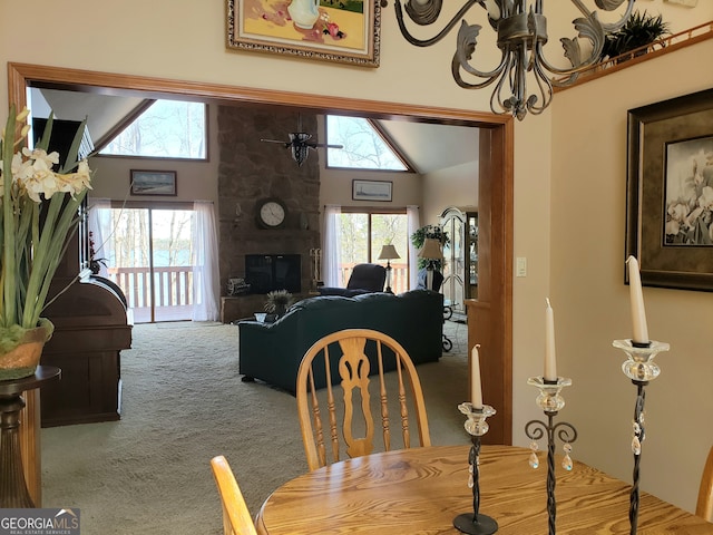 carpeted dining area featuring high vaulted ceiling, a fireplace, and a notable chandelier