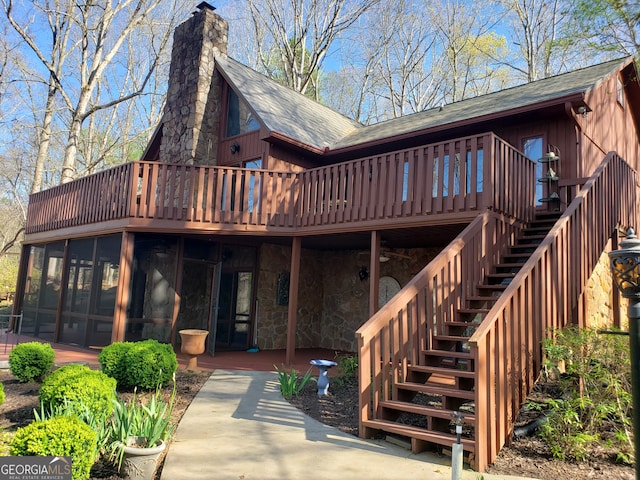 rear view of house with a deck, a patio area, and a sunroom