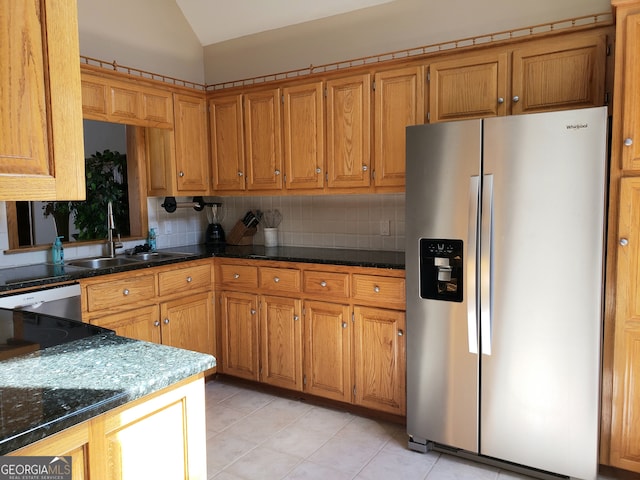 kitchen featuring backsplash, vaulted ceiling, stainless steel fridge, and sink