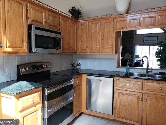 kitchen with dark stone countertops, backsplash, sink, and stainless steel appliances