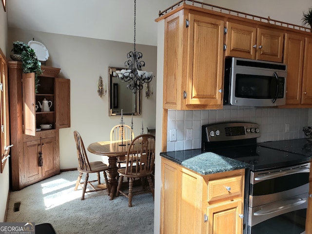 kitchen featuring hanging light fixtures, dark stone countertops, backsplash, stainless steel appliances, and an inviting chandelier