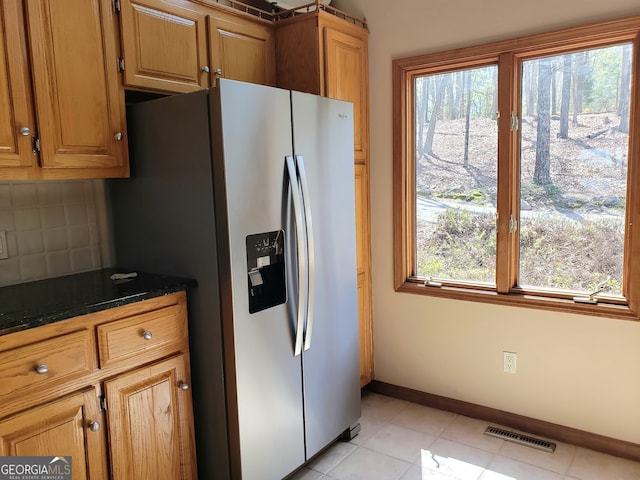 kitchen with plenty of natural light, stainless steel fridge with ice dispenser, light tile floors, and tasteful backsplash