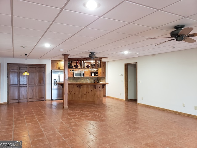 interior space with indoor bar, ceiling fan, light tile floors, and a paneled ceiling