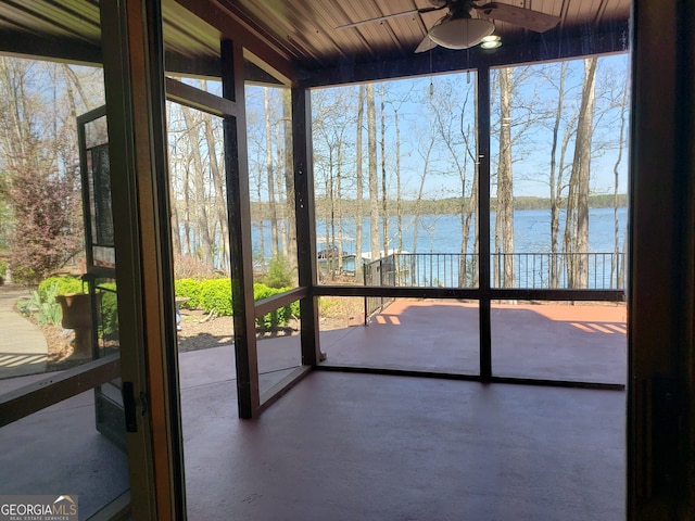 unfurnished sunroom featuring ceiling fan and a water view