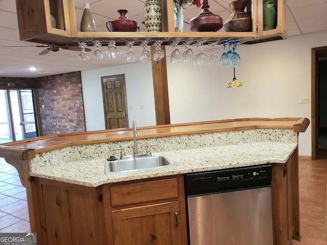 kitchen featuring light stone counters, sink, light tile floors, and stainless steel dishwasher