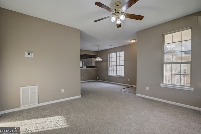 unfurnished room featuring ceiling fan, a wealth of natural light, and light colored carpet