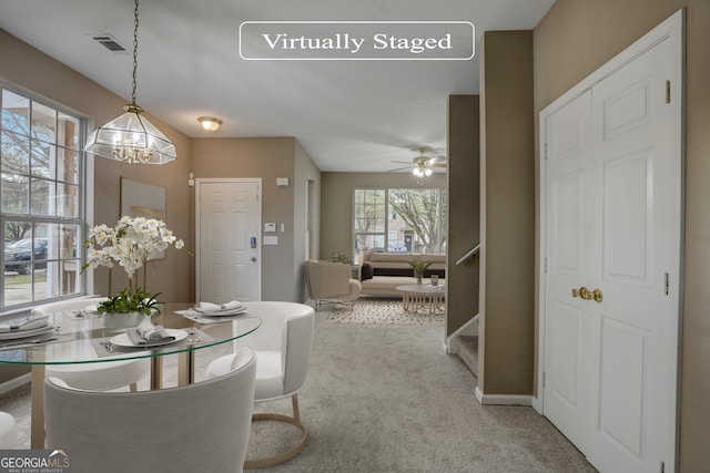 carpeted dining area featuring ceiling fan with notable chandelier