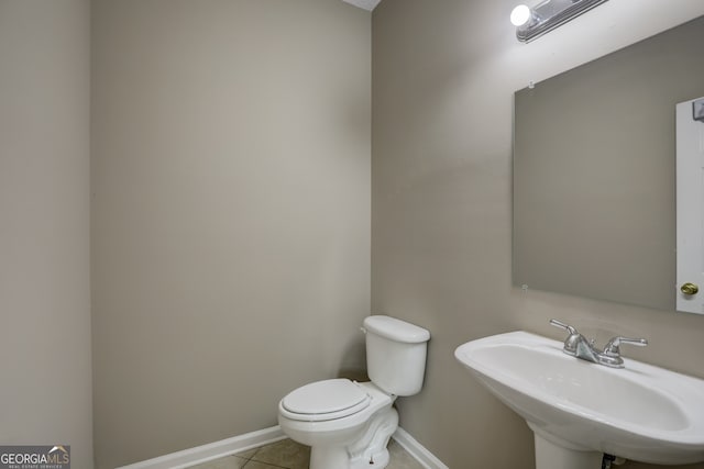 bathroom featuring toilet, sink, and tile flooring