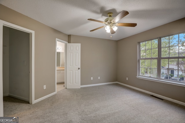 empty room featuring a textured ceiling, ceiling fan, and light colored carpet