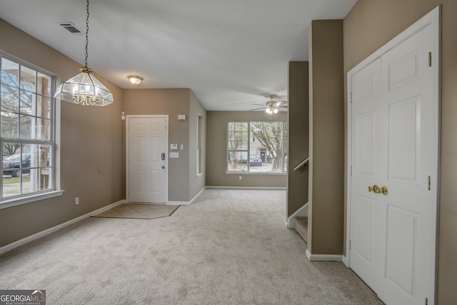 carpeted entrance foyer featuring ceiling fan with notable chandelier