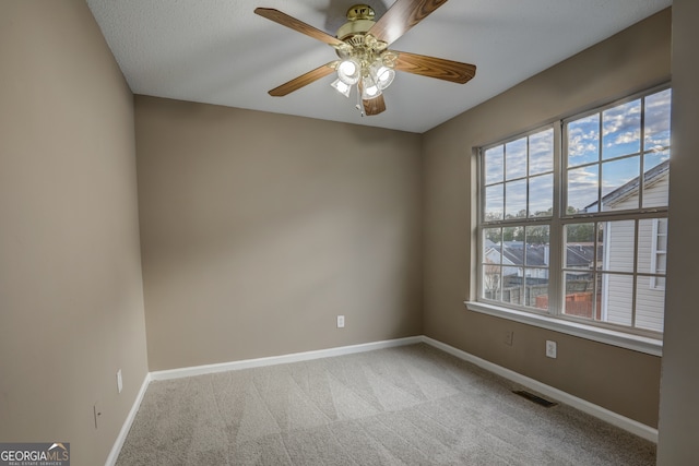 spare room with ceiling fan, a wealth of natural light, and light colored carpet