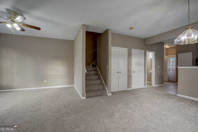 interior space with ceiling fan with notable chandelier and light colored carpet