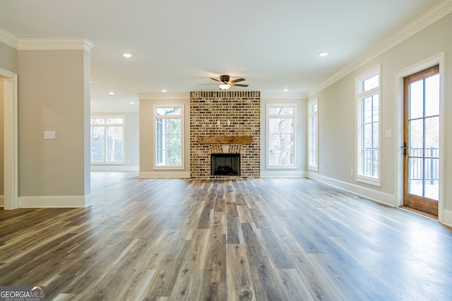 unfurnished living room with ceiling fan, a brick fireplace, a healthy amount of sunlight, and wood-type flooring