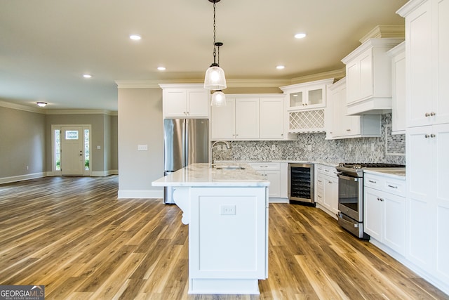 kitchen with white cabinets, beverage cooler, hanging light fixtures, and stainless steel appliances