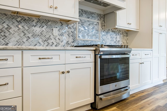 kitchen featuring gas stove, tasteful backsplash, white cabinetry, custom exhaust hood, and light wood-type flooring