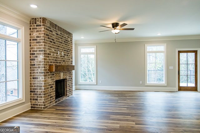 unfurnished living room featuring plenty of natural light, ceiling fan, dark hardwood / wood-style floors, and a fireplace