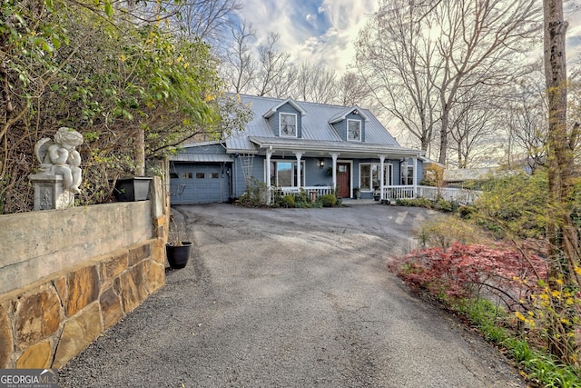 cape cod-style house featuring a garage and a porch