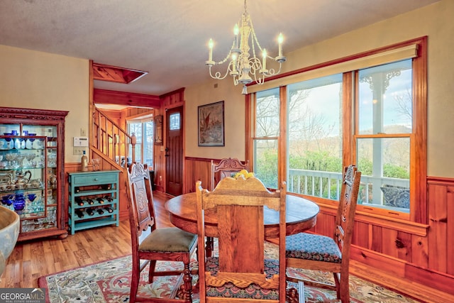 dining area with wooden walls, an inviting chandelier, and wood-type flooring