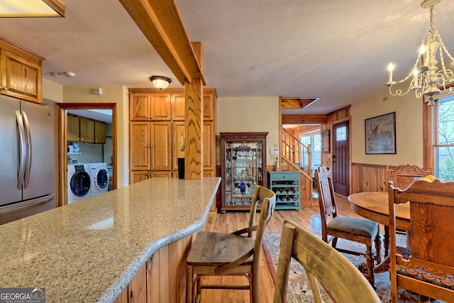 kitchen featuring light stone countertops, light hardwood / wood-style floors, stainless steel fridge, and a healthy amount of sunlight