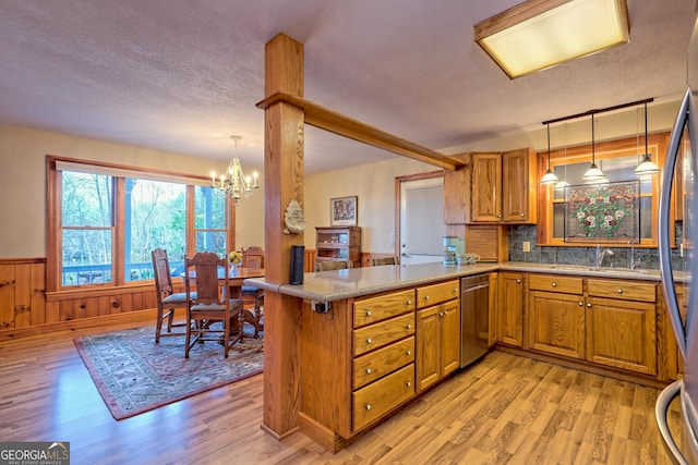 kitchen featuring pendant lighting, light hardwood / wood-style floors, wood walls, and kitchen peninsula