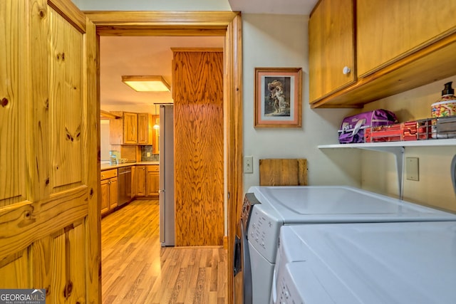 laundry room featuring cabinets, light wood-type flooring, and washer and clothes dryer