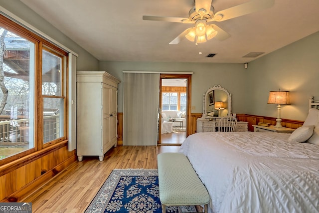 bedroom with ceiling fan, light wood-type flooring, and wood walls